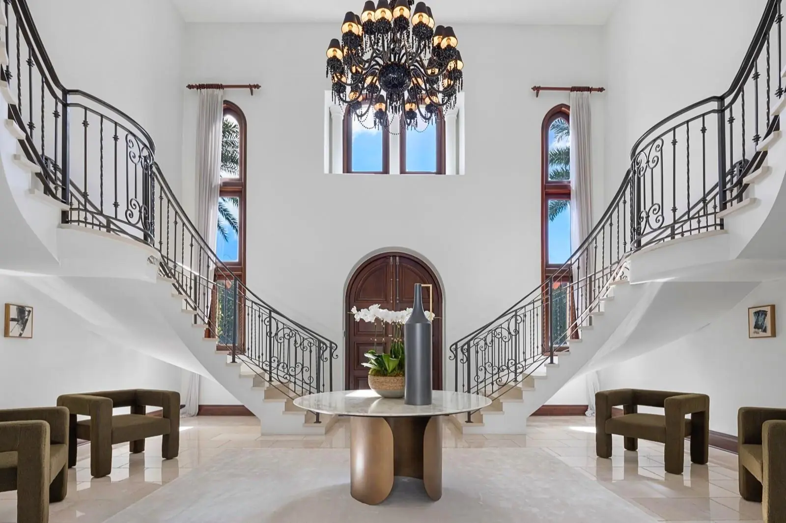 Grand two-story foyer with a double curved staircase, wrought-iron railings and a chandelier